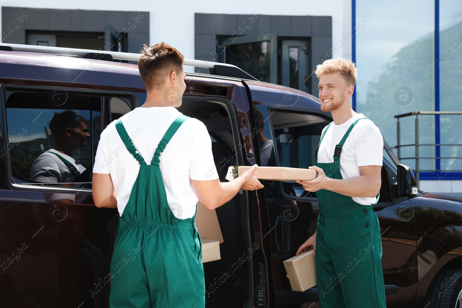 Photo of Young couriers with parcels near delivery car outdoors