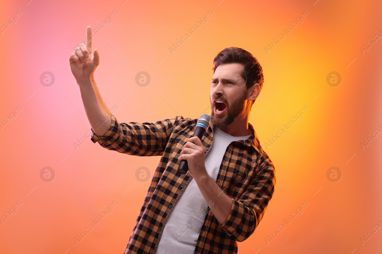 Photo of Handsome man with microphone singing in color lights