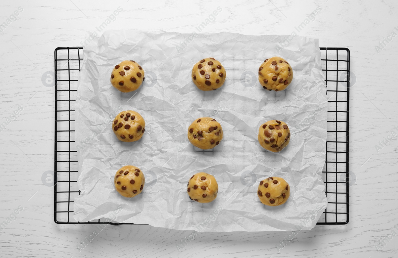 Photo of Uncooked chocolate chip cookies on white wooden table, top view