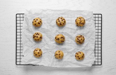 Photo of Uncooked chocolate chip cookies on white wooden table, top view