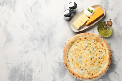 Delicious cheese pizza, oil and different kinds of cheese on light grey textured table, flat lay. Space for text