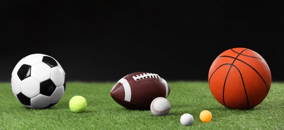Many different sports balls on green grass against black background, space for text. Banner design