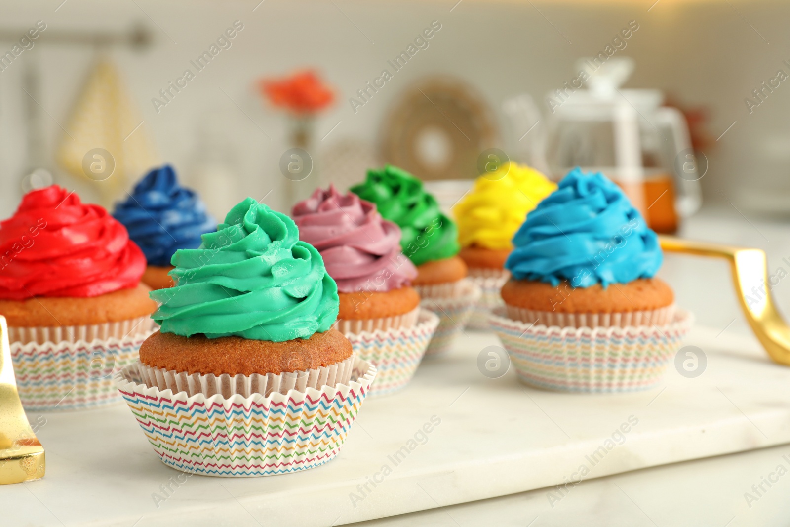 Photo of Delicious cupcakes with colorful cream on white board, closeup