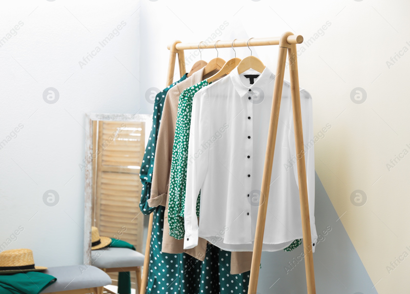 Photo of Wardrobe rack with women's clothes at color wall in room