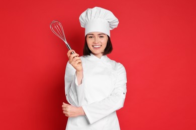 Photo of Happy confectioner holding whisk on red background