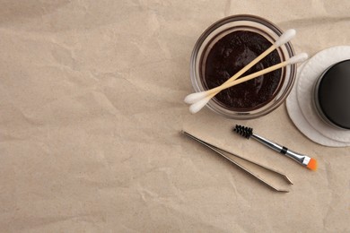 Flat lay composition with eyebrow henna and tools on crumpled paper. Space for text