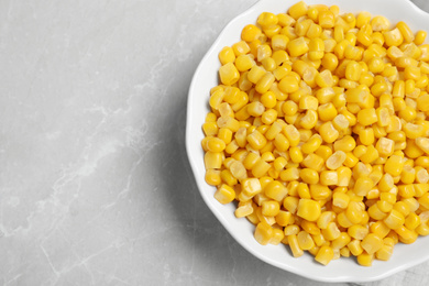 Photo of Delicious canned corn in bowl on marble table, top view. Space for text