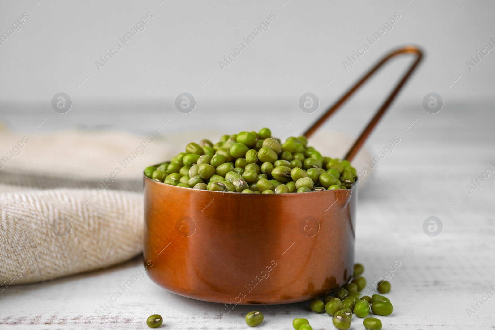 Photo of Scoop with mung beans on white wooden table, closeup