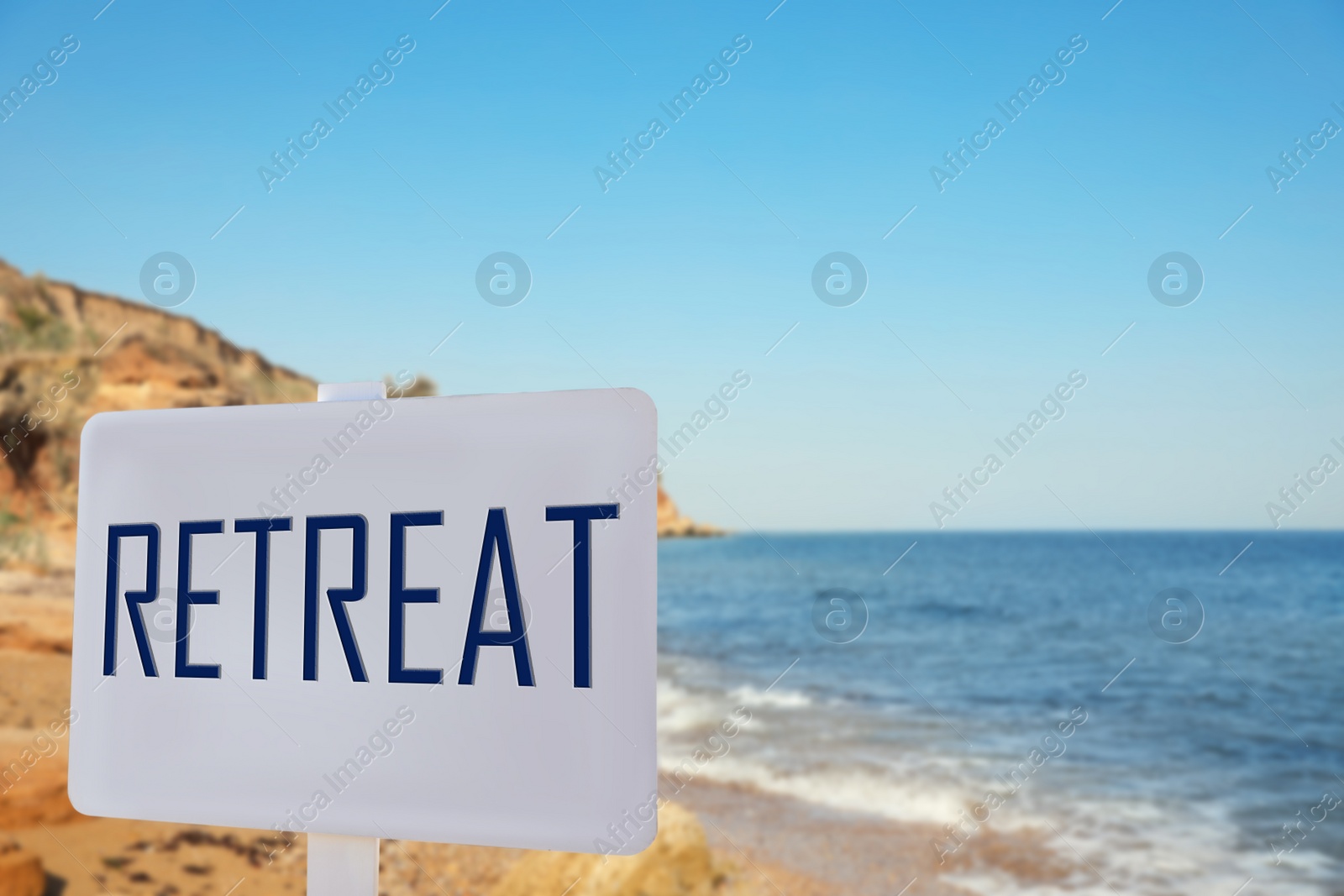 Image of Wooden sign with word Retreat and picturesque view of beautiful beach