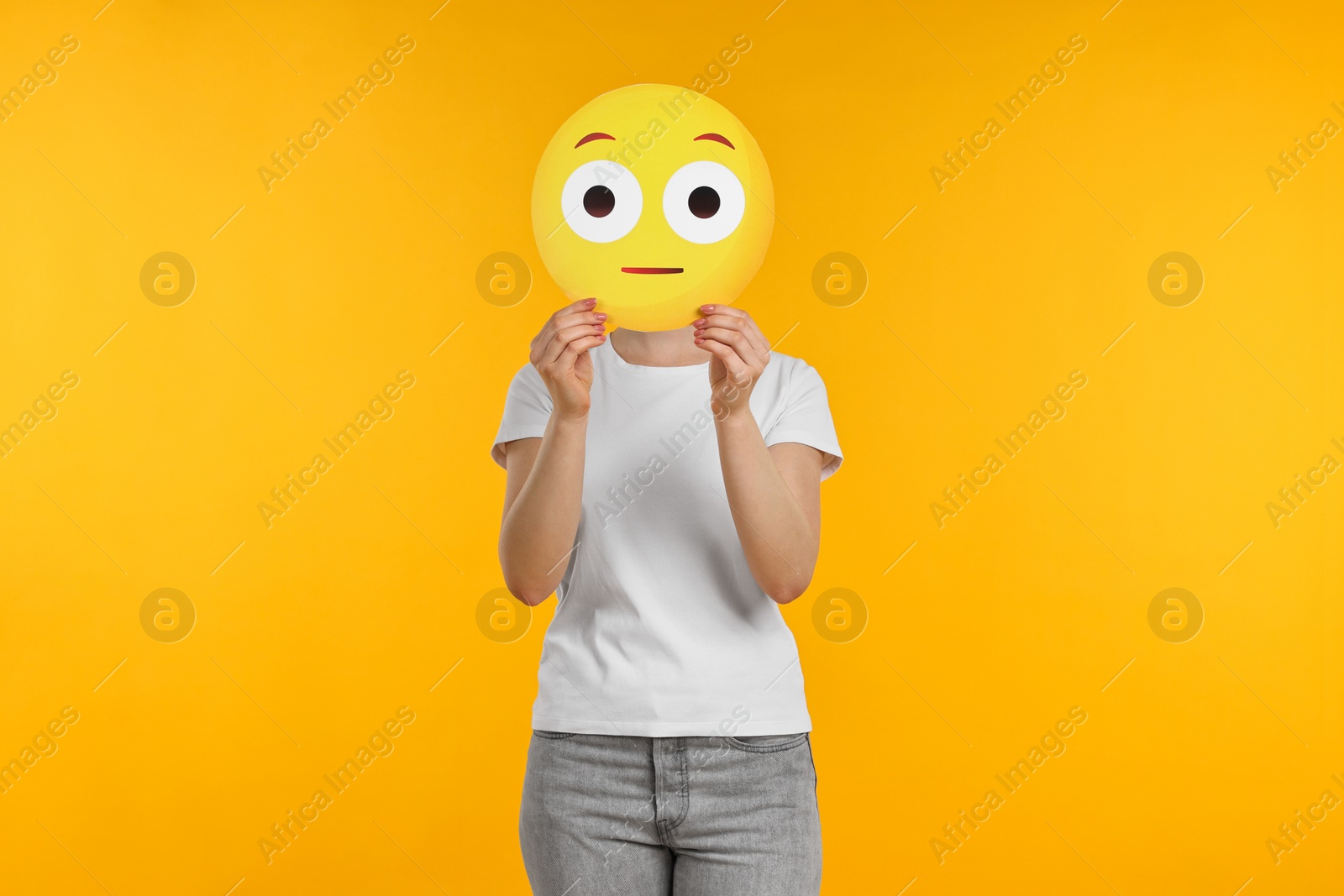 Photo of Woman covering face with surprised emoticon on yellow background