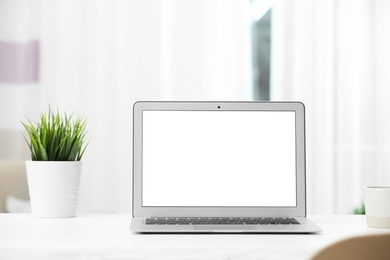 Laptop with blank screen on table indoors. Space for text