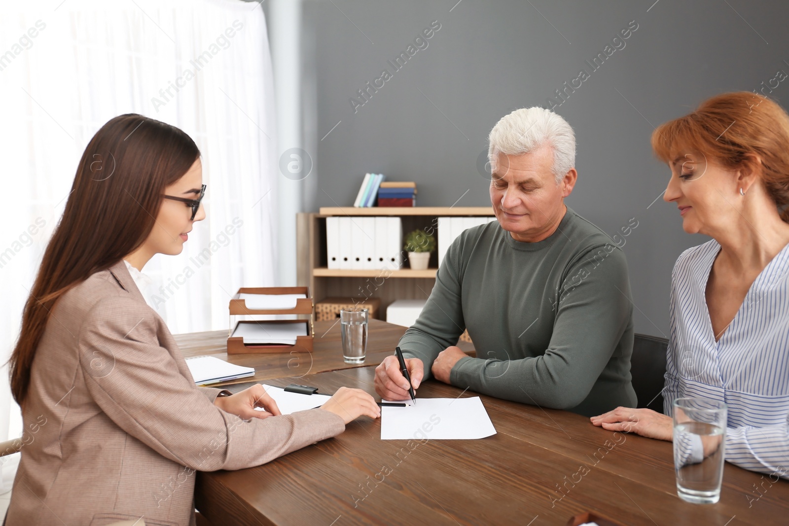 Photo of Young lawyer consulting senior couple in office