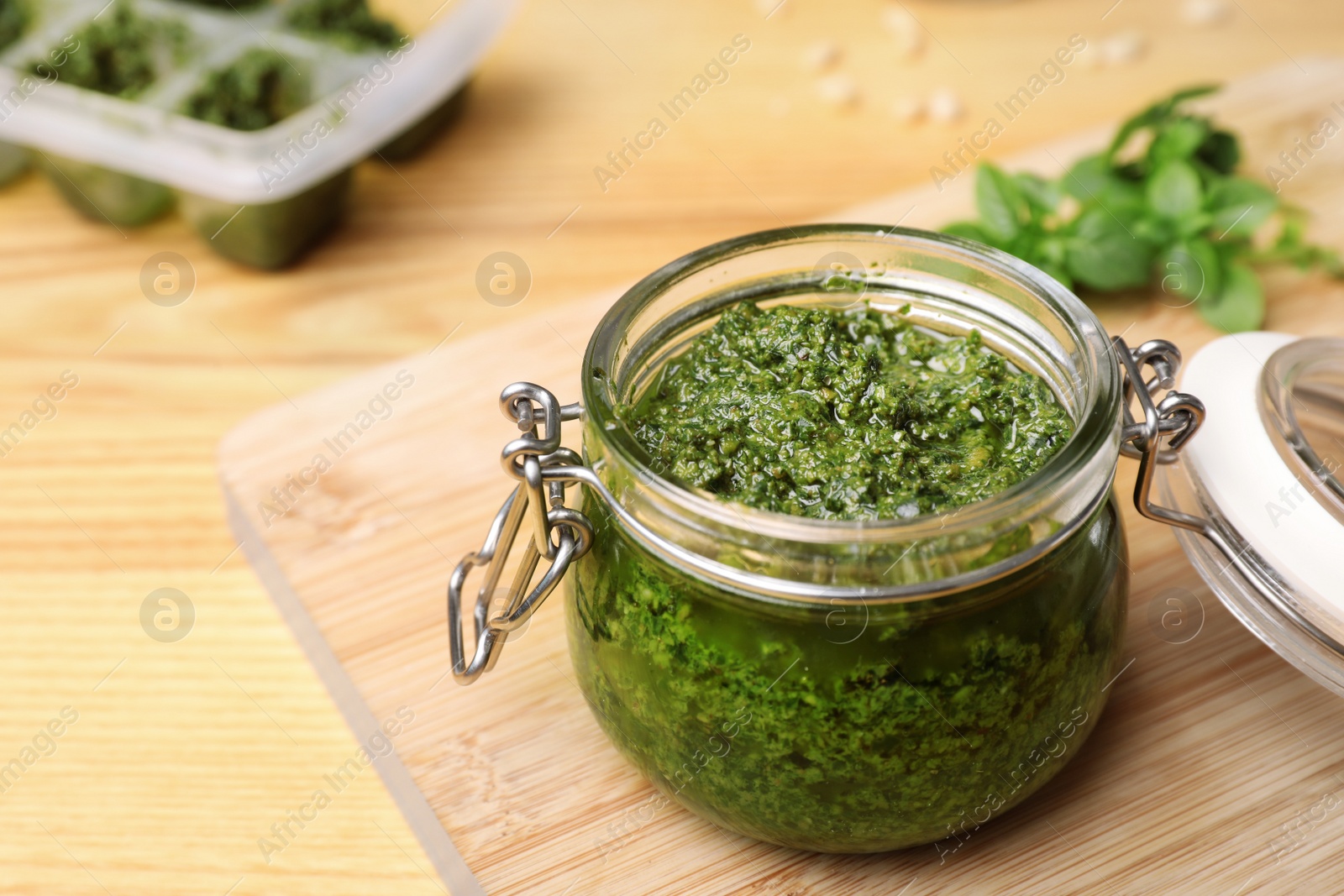 Photo of Homemade basil pesto sauce in glass jar on wooden table