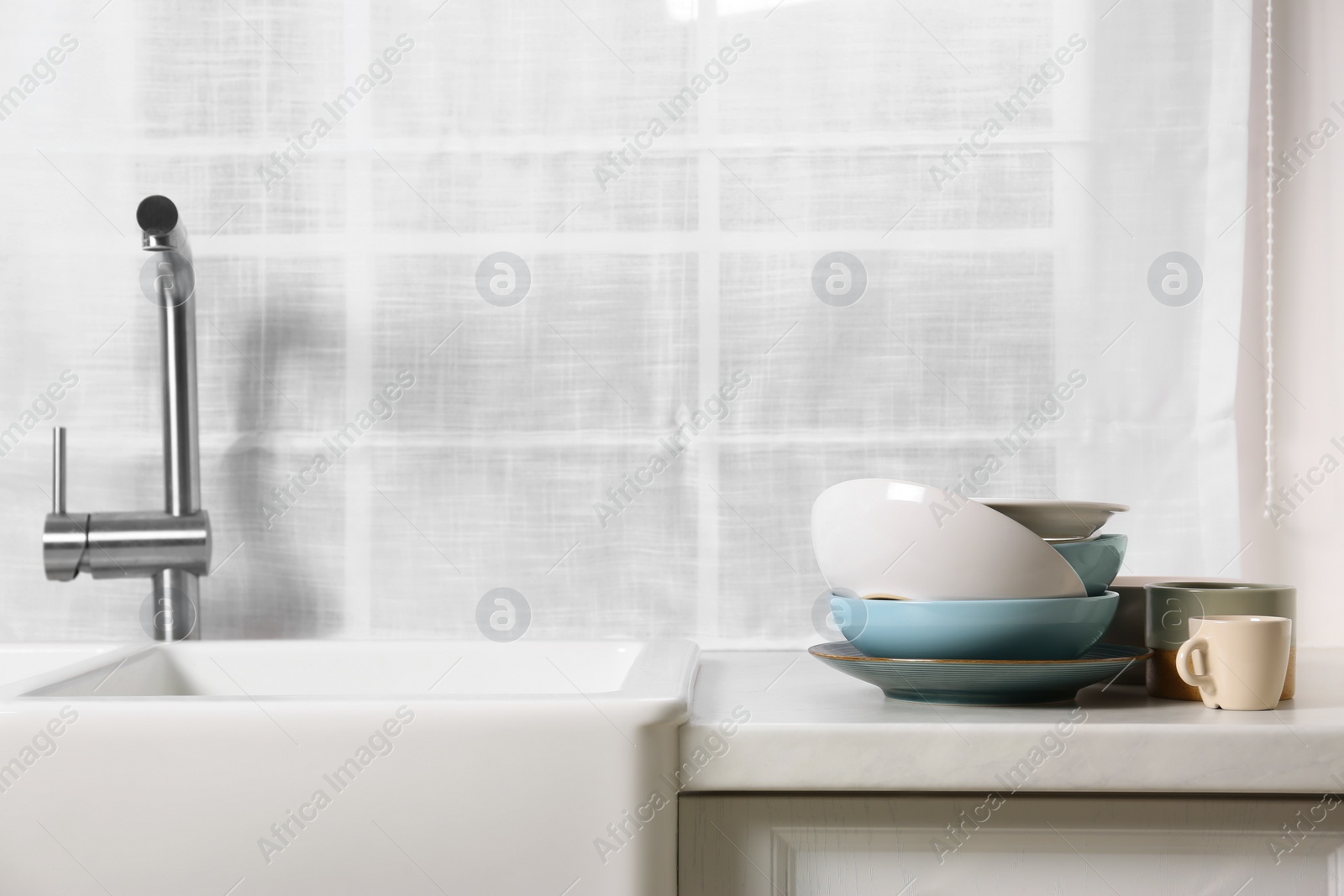 Photo of Clean tableware on light countertop in kitchen, space for text