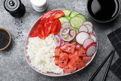 Delicious poke bowl with salmon and vegetables served on grey table, flat lay
