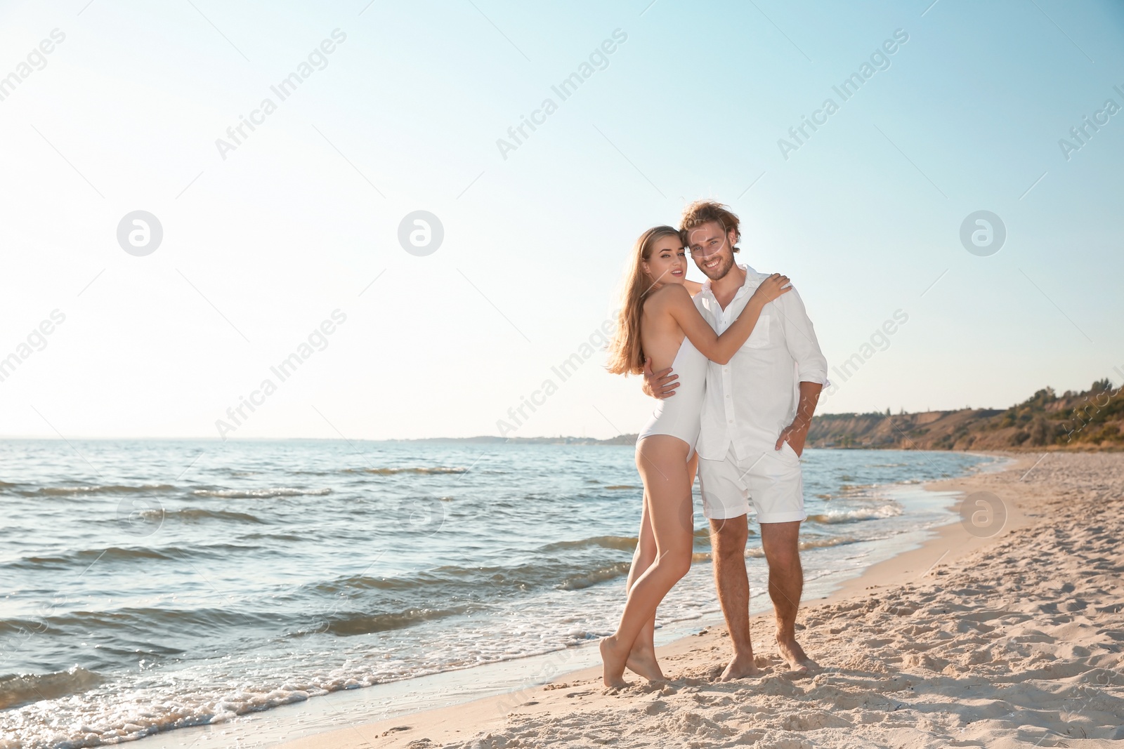 Photo of Romantic young couple spending time together on beach. Space for text