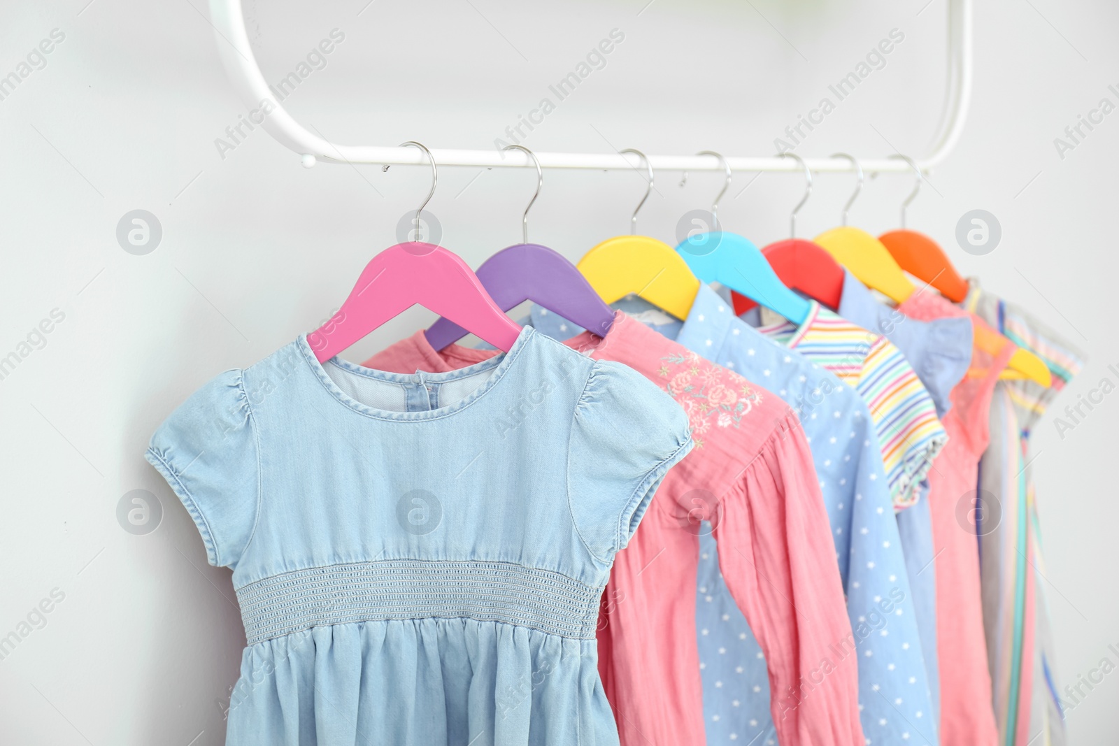 Photo of Rack with different clothes on light background, closeup