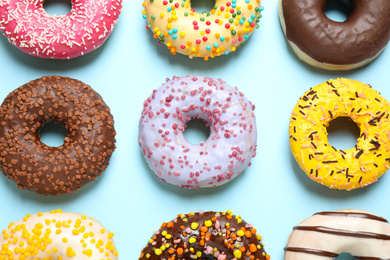 Delicious glazed donuts on light blue background, flat lay