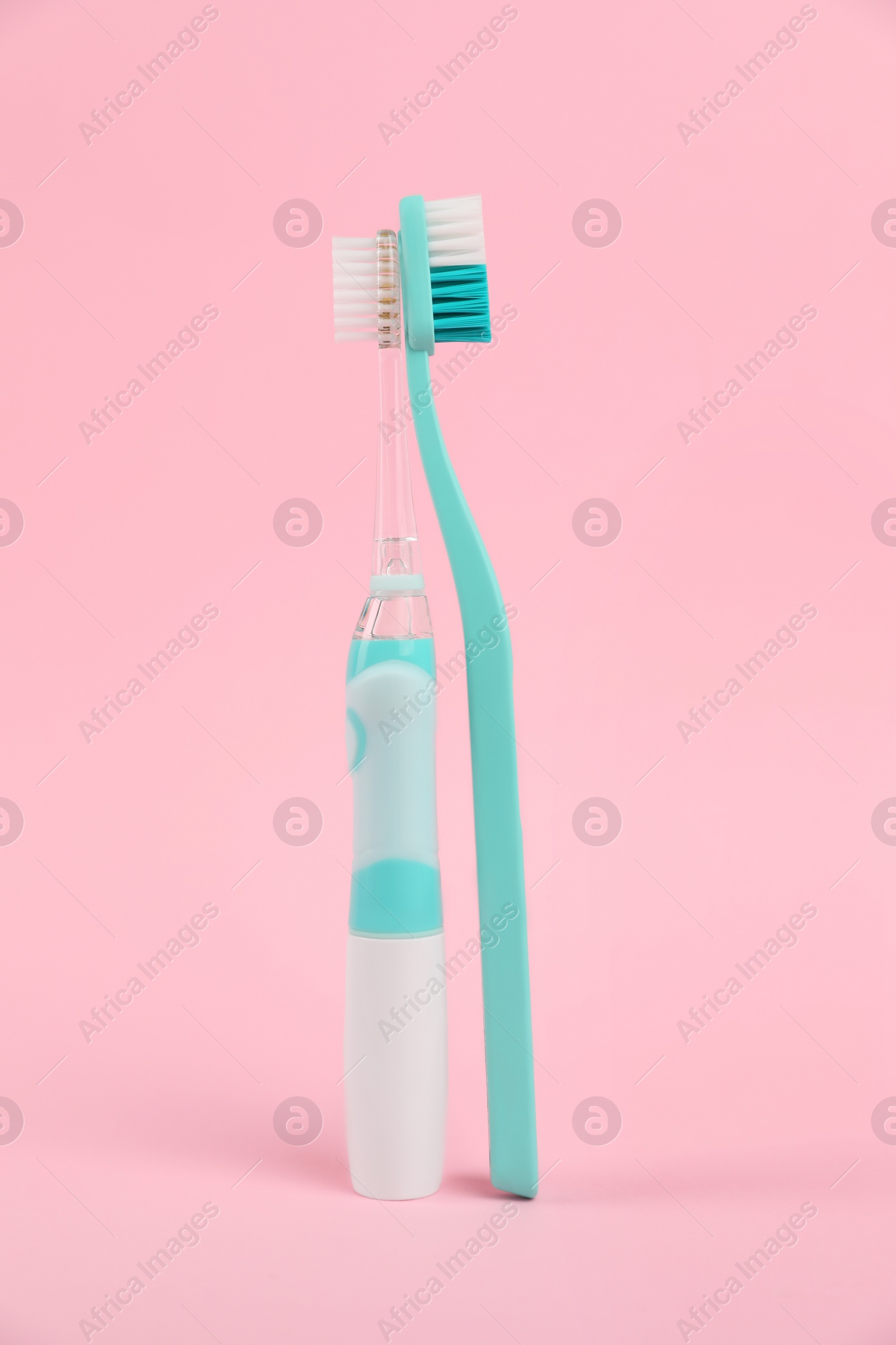 Photo of Electric and plastic toothbrushes on pink background. Dental care