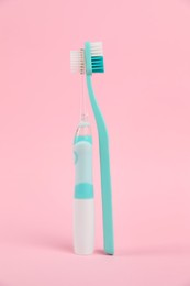 Photo of Electric and plastic toothbrushes on pink background. Dental care