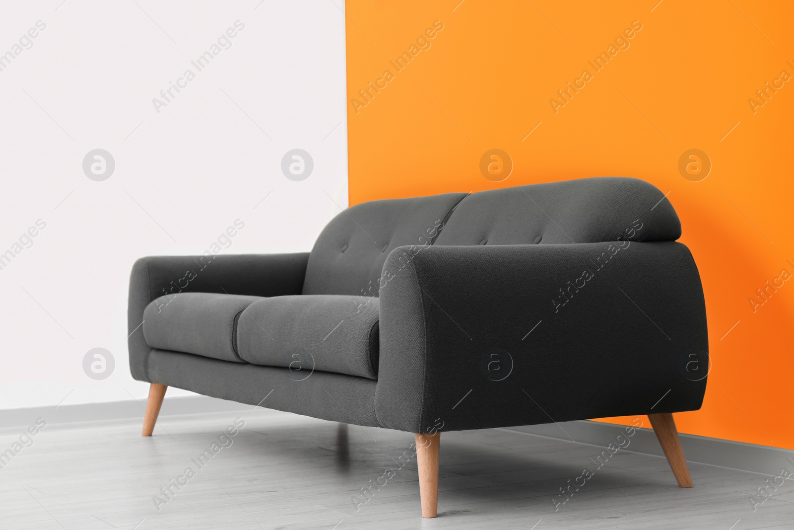 Photo of Stylish room with cosy sofa near orange wall. Interior design