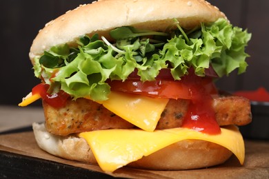 Photo of Delicious burger with tofu, fresh vegetables and sauce on board, closeup