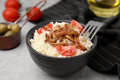 Photo of Tasty couscous with mushrooms and tomatoes on grey table, closeup