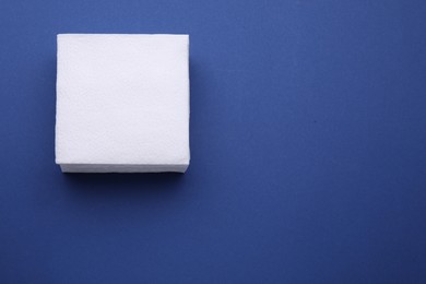 Photo of Stack of clean paper tissues on blue background, top view. Space for text