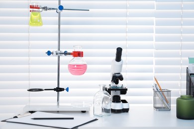 Photo of Laboratory analysis. Flasks with liquids and microscope on white table