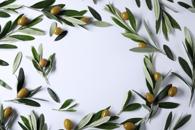 Frame made of fresh green olives and leaves on white background, flat lay. Space for text