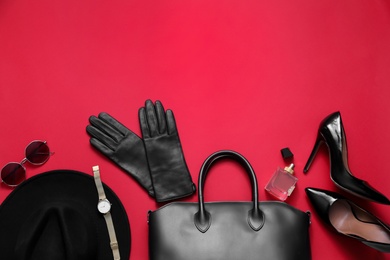 Flat lay composition with stylish black leather gloves, shoes and accessories on red background. Space for text