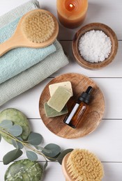 Flat lay composition with different spa products and burning candle on white wooden table