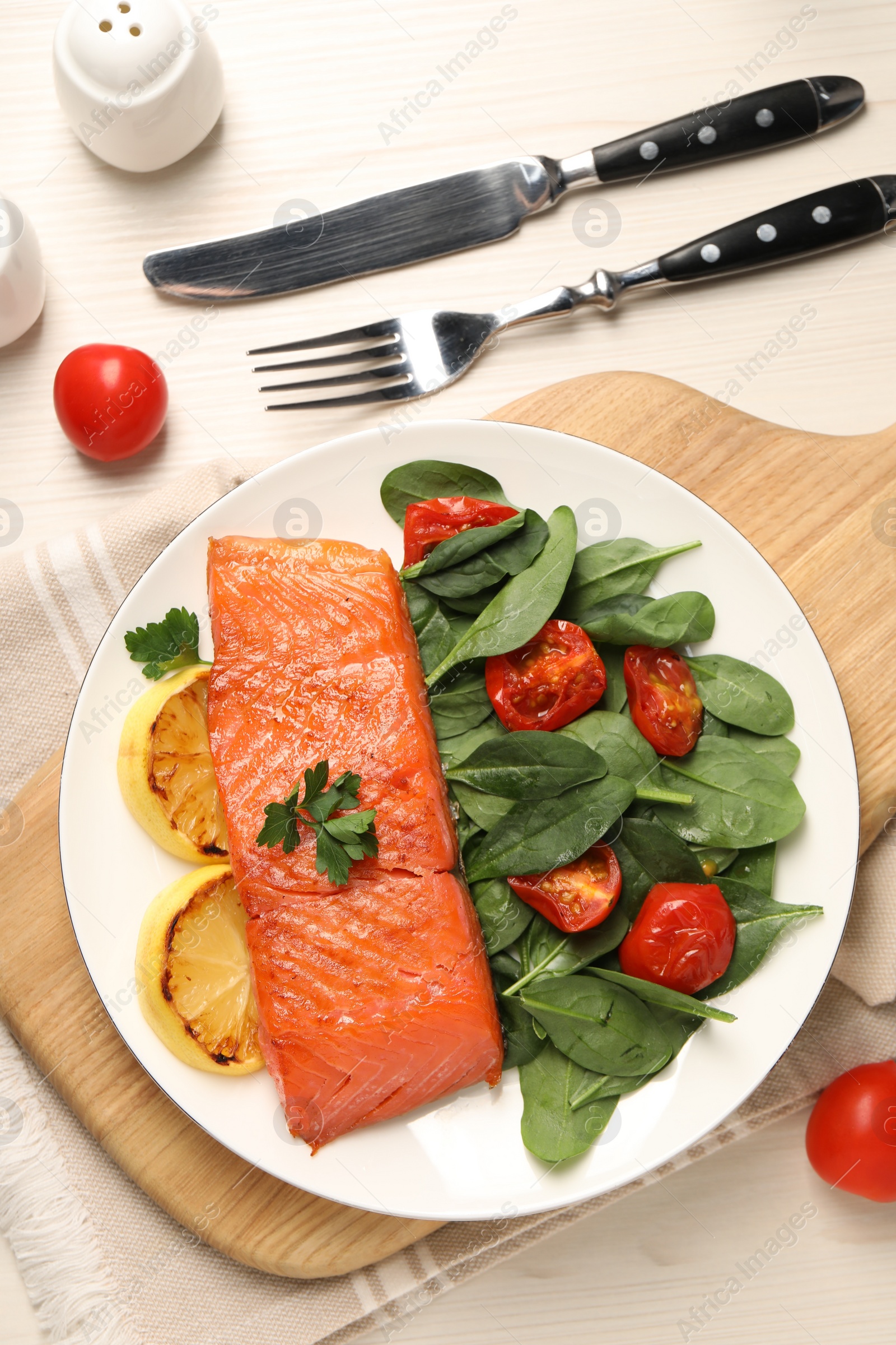 Photo of Tasty grilled salmon with basil, tomatoes and lemon on white wooden table, flat lay