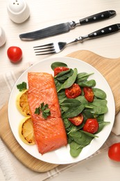 Photo of Tasty grilled salmon with basil, tomatoes and lemon on white wooden table, flat lay