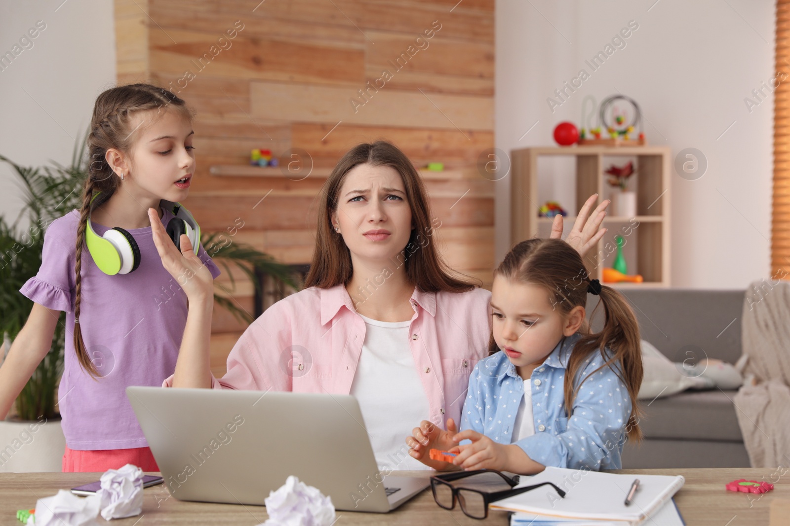 Photo of Children disturbing stressed woman in living room. Working from home during quarantine