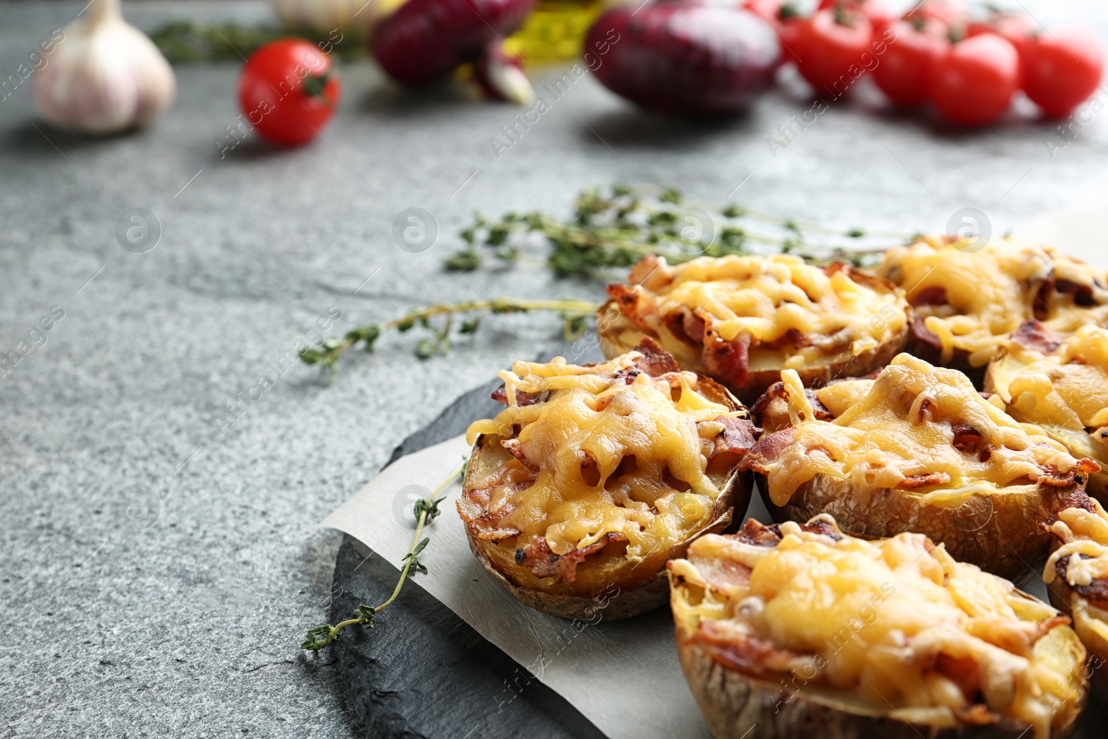 Photo of Slate plate with baked potatoes on table, closeup. Space for text