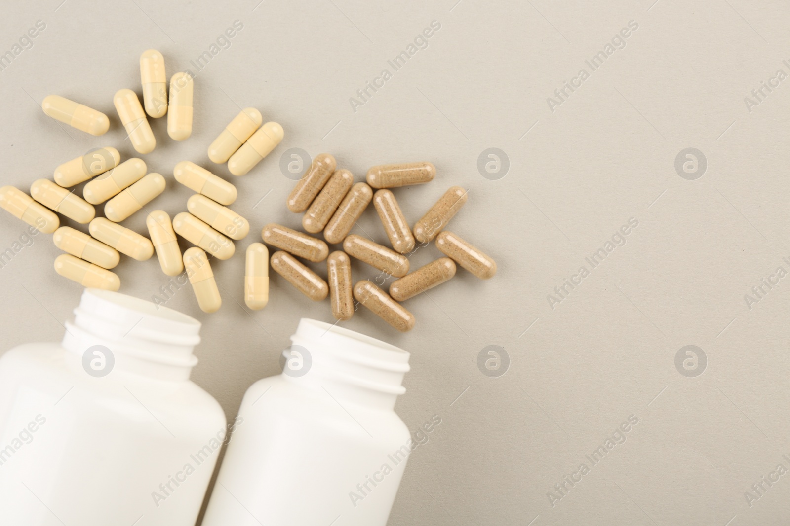 Photo of Bottles and different vitamin capsules on light background, flat lay. Space for text