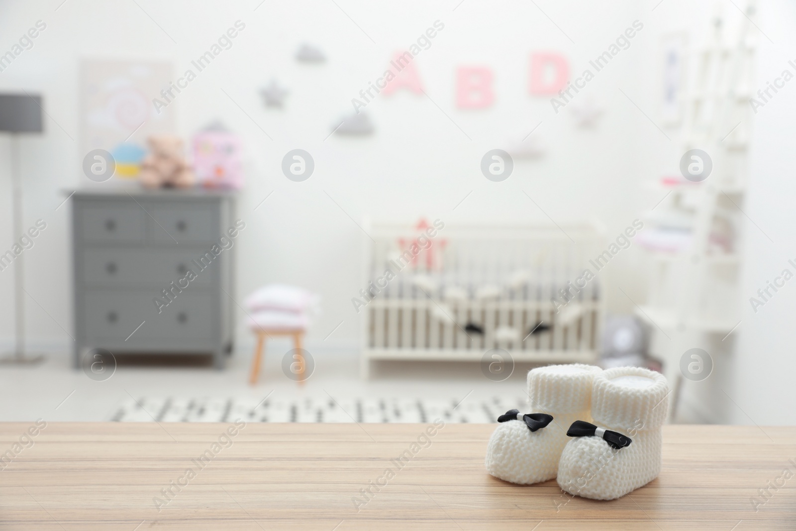 Photo of Small baby booties on wooden table in room. Space for text