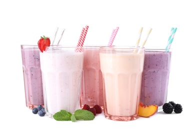 Different fresh tasty milk shakes in glasses with ingredients on white background