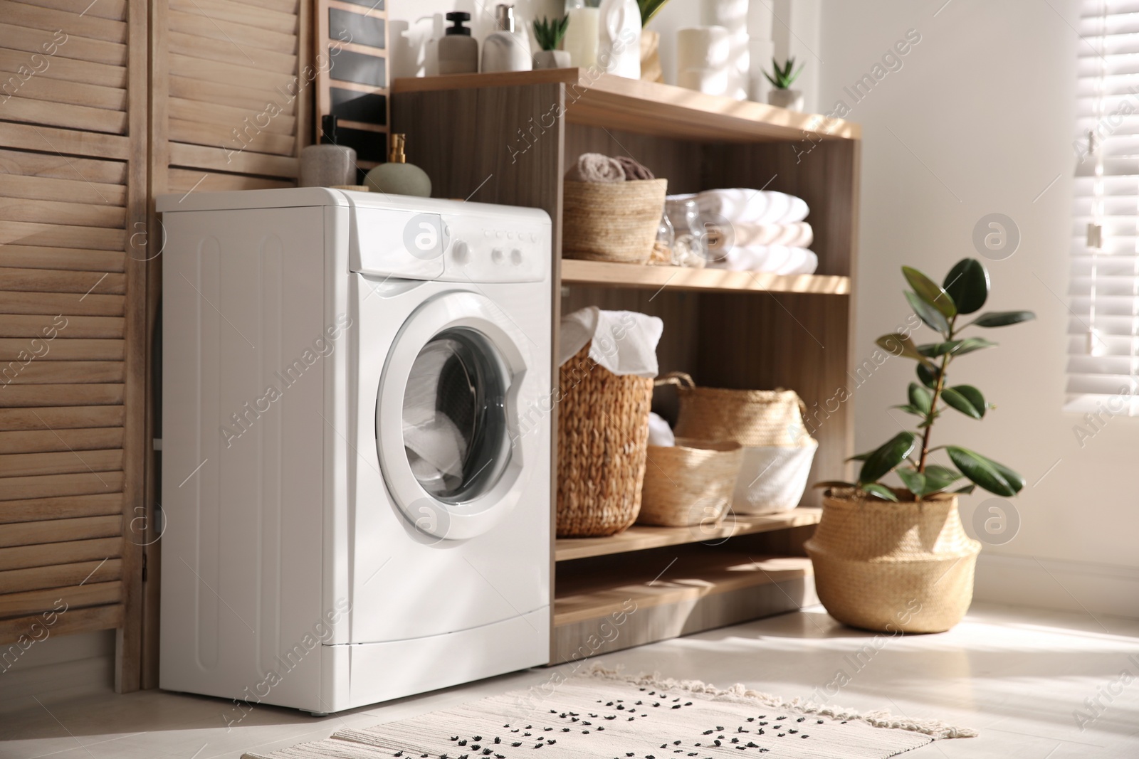 Photo of Modern washing machine and shelving unit in laundry room interior