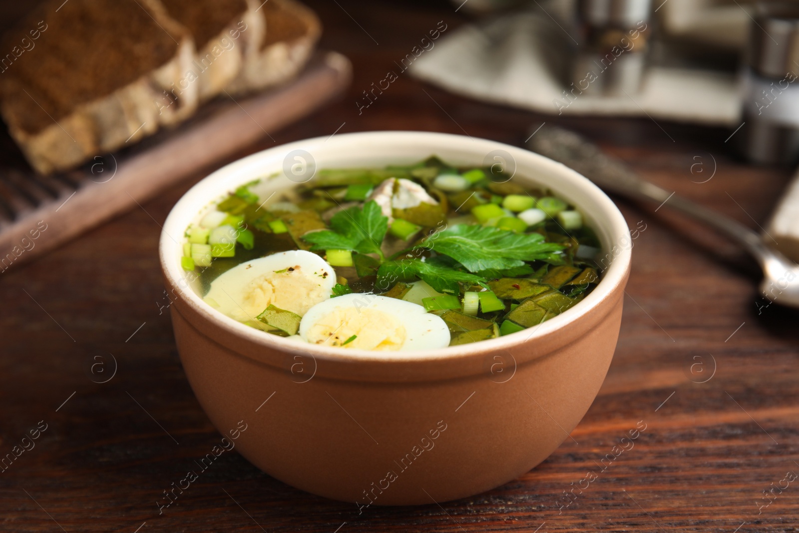 Photo of Delicious sorrel soup with eggs on brown wooden table
