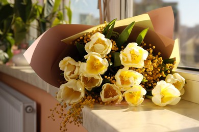 Photo of Bouquet with beautiful tulips and mimosa flowers on windowsill indoors