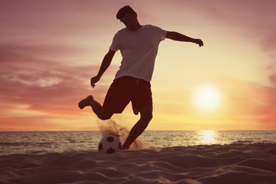 Photo of Man playing football on beach at sunset