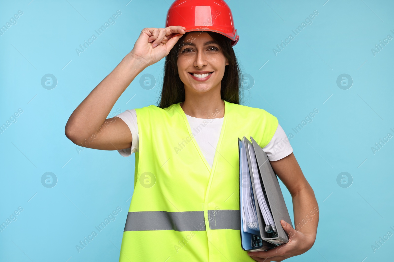 Photo of Architect in hard hat with folders on light blue background