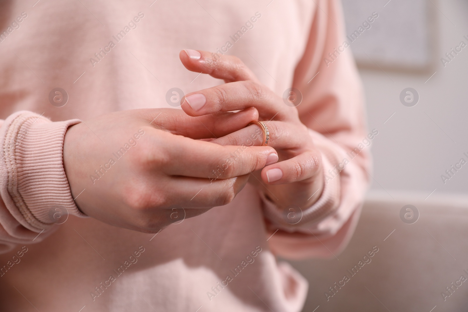 Photo of Woman taking off wedding ring indoors, closeup. Divorce concept