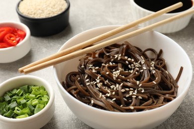 Tasty buckwheat noodles (soba) with sesame served on light grey table, closeup