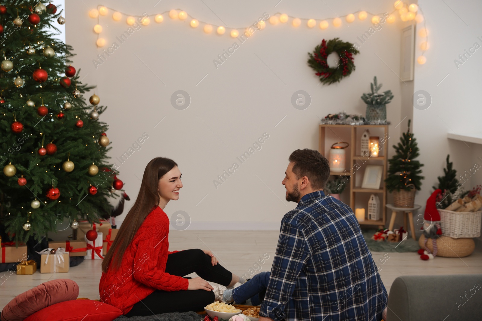 Photo of Happy couple spending time at TV area in cosy room. Christmas atmosphere