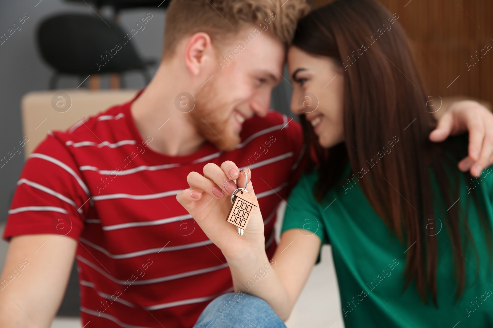 Photo of Young couple with key from their new house indoors, closeup. Moving day