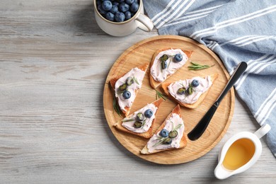 Photo of Tasty sandwiches with cream cheese, honey and berries on white wooden table, flat lay. Space for text