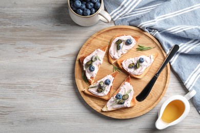 Tasty sandwiches with cream cheese, honey and berries on white wooden table, flat lay. Space for text